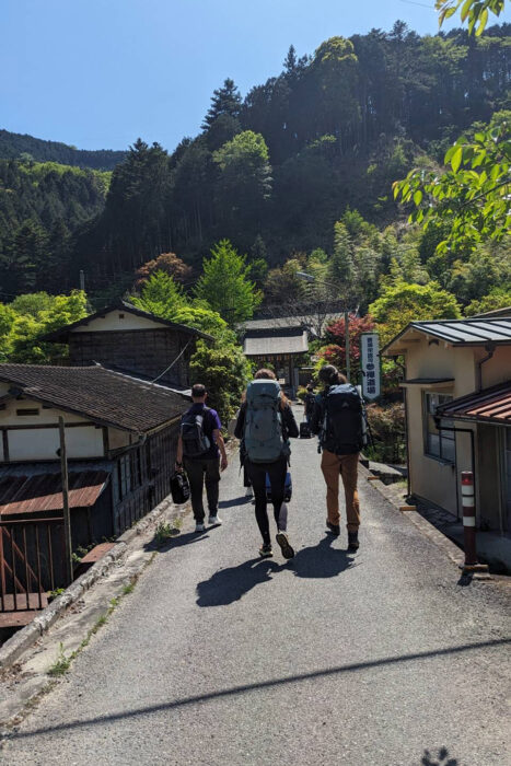 Japón contra el turismo de masas: ¿es 2026 un buen momento para visitar la tierra del Sol Naciente? 4 Turistas arrastrando sus mochilas por un pequeño pueblo del Japón rural