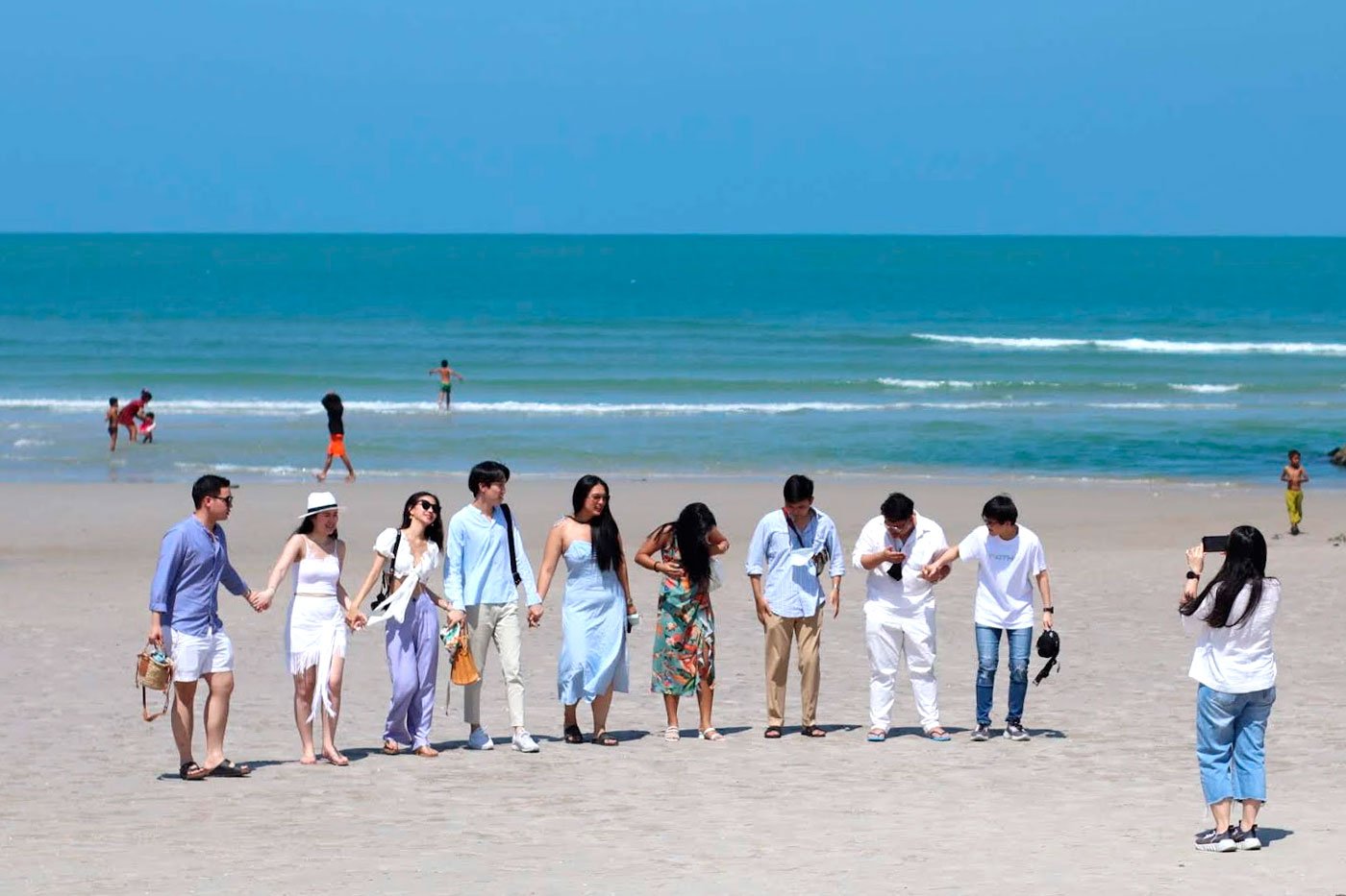Thai tourists taking a group photo on Khao Takiab Beach.