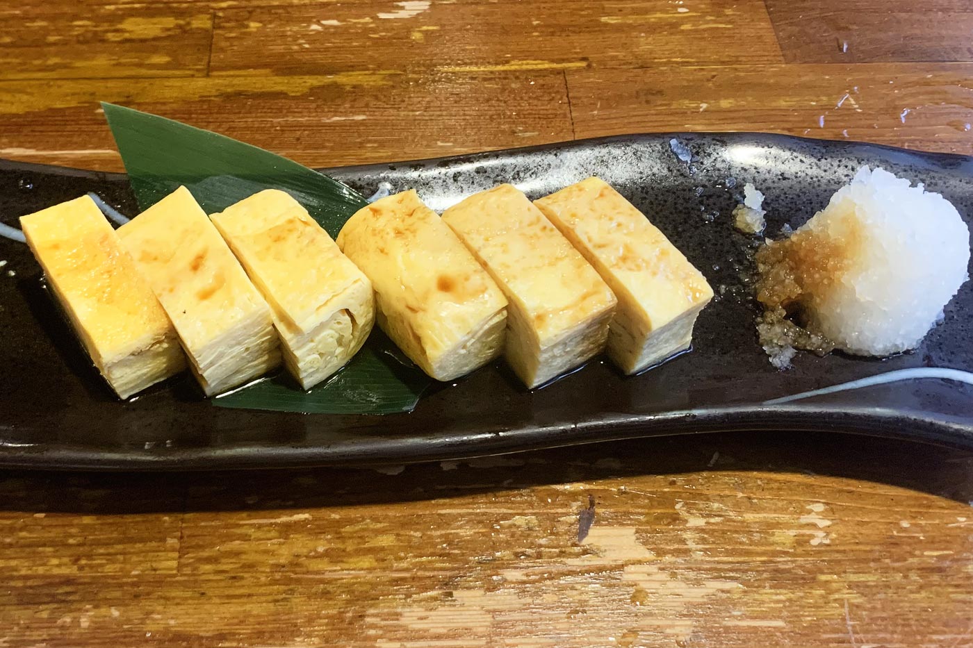 Serving of tamago-yaki as served in izakaya taverns: cut into small bites and with grated turnip and soy sauce on the side