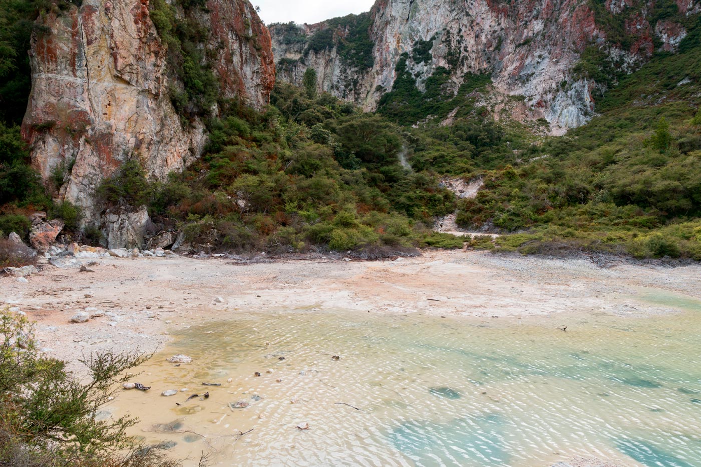 The bright blue color contrasts with the deep red and white of the cliffs that surround it.