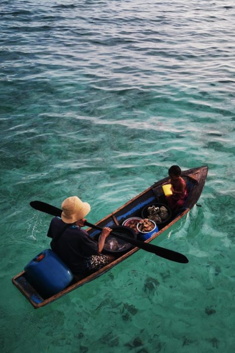 Padre e hijo de escasos dos años y medio, achicando agua del bote y  navegando durante la puesta de sol