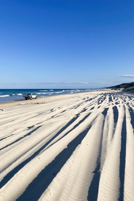 Arena blanda a la derecha de la foto y todoterreno conduciendo cerca de la playa
