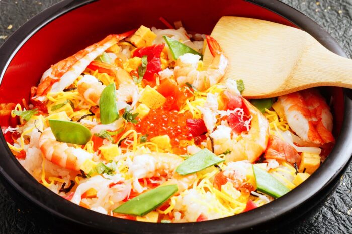 Ración de chirashi sushi, con algo de verduras y tiras de tortilla para acompañar