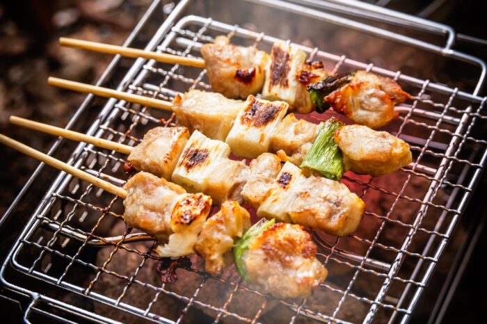 Brochetas de yakitori cocinándose en la parrilla, al modo tradicional