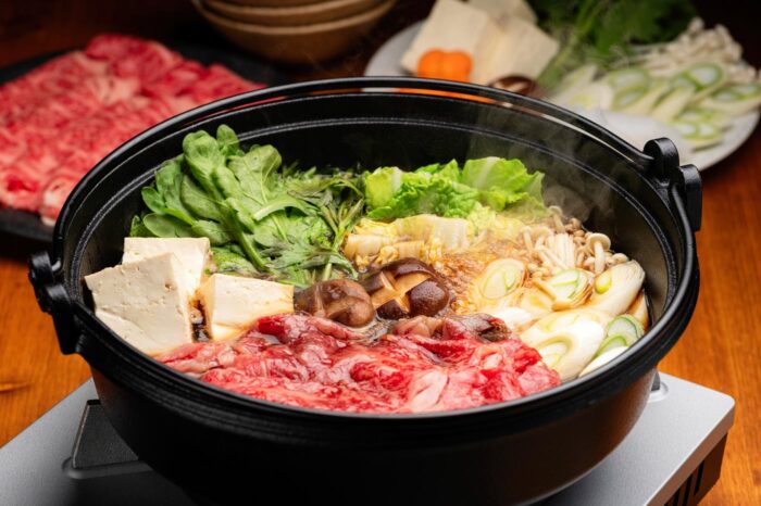Puchero de sukiyaki con su carne, sus setas, sus verduras, y un poco de tofu para rematar