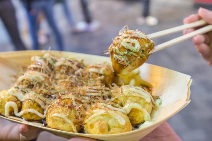 Ración de tako-yaki con sus condimentos habituales: salsa especial, mayonesa, trocitos de alga y copos de atún