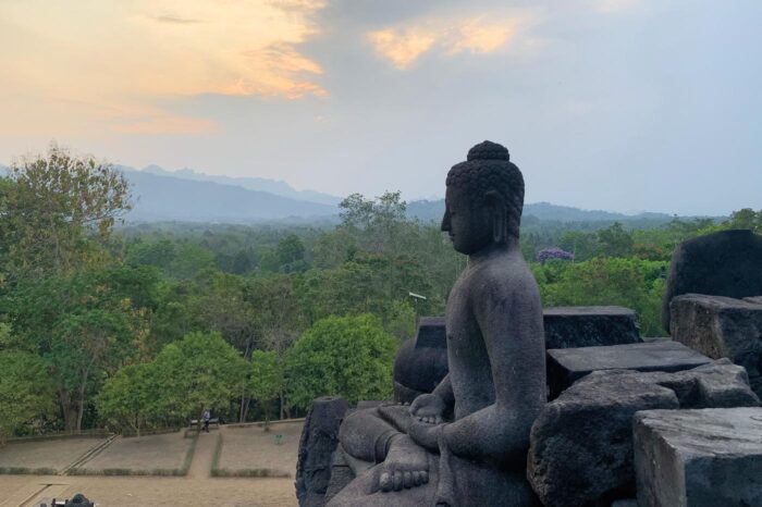 Estatua de Buda meditando, con la selva javanesa en lontananza