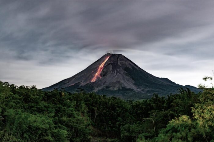 La silueta del volcán Merapi, con la colada de lava cayendo por la ladera, surge de entre la espesura