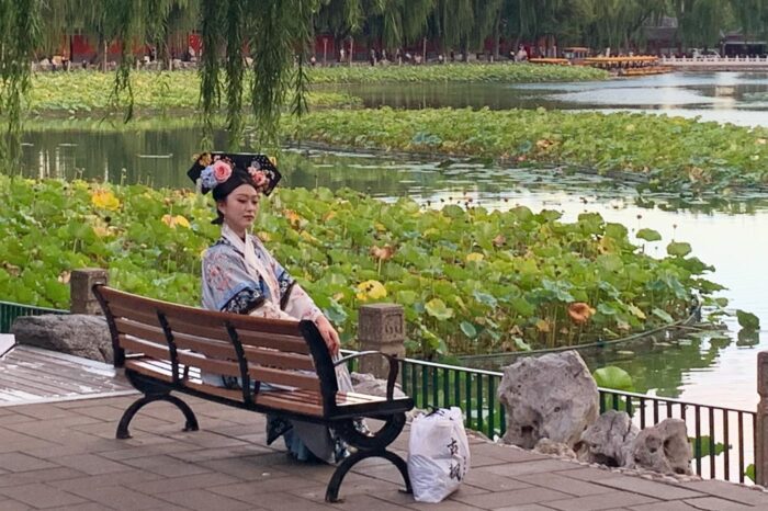 Joven china vestida de época, descansando en un banco después de sacarse fotos durante toda la mañana con sus amigas