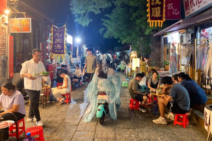 Chica vistiendo un cosplay de época y en moto, en un callejón de Luoyang