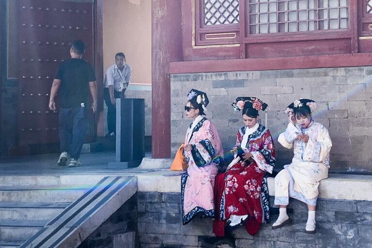 Turistas chinas tomándose un descanso en la Ciudad Prohibida de Pekín… móvil en mano